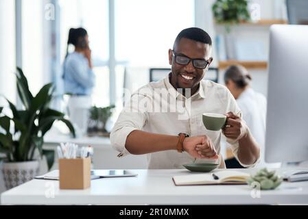 Pünktlich mit einer anderen Frist. Ein junger Geschäftsmann, der die Uhrzeit auf seiner Armbanduhr überprüft, während er in einem Büro arbeitet. Stockfoto