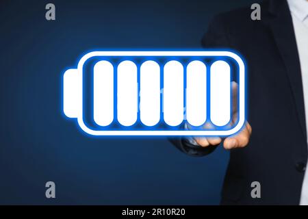 Ein Geschäftsmann, der bei der Legende der vollen Batterie auf farbigem Hintergrund vorführt, Nahaufnahme Stockfoto