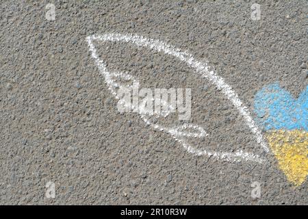 Herz und Flügel mit blauen und gelben Kreiden auf Asphalt im Freien, Nahaufnahme. Platz für Text Stockfoto