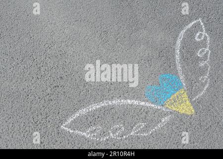 Herz und Flügel mit blauen und gelben Kreiden auf Asphalt im Freien. Platz für Text Stockfoto