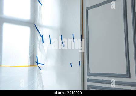 Fenster mit Kunststofffolie und Isolierband im Innenbereich Stockfoto