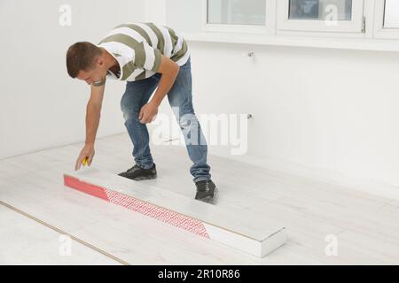 Professioneller Arbeiter, der neue Laminatböden im Innenbereich installiert Stockfoto