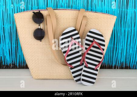 Stilvolle Flip-Flops, Tasche und Sonnenbrille auf weißem Holztisch Stockfoto