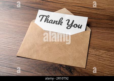 Umschlag und Karte mit Phrase Danke auf Holztisch Stockfoto