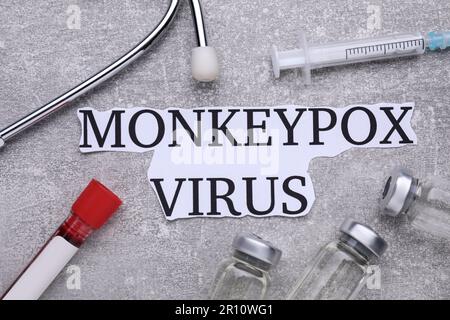 Flache Laienzusammensetzung mit den Wörtern Monkeypox Virus und Reagenzglas auf hellgrauem Tisch Stockfoto