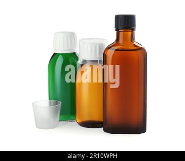 Flaschen mit Sirup mit Messbechern auf weißem Hintergrund. Husten und Erkältungsmedizin Stockfoto