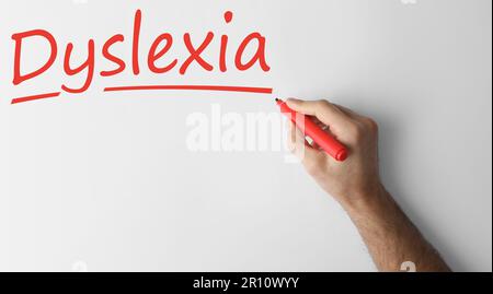 Ein Mann schreibt das Wort Dyslexia auf weißem Hintergrund, Nahaufnahme. Bannerdesign Stockfoto