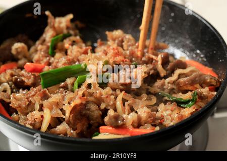 Japanisches Rindfleisch mit grünen Zwiebeln, Karotten und Zwiebelscheiben mit Chopstick, Nahaufnahme Stockfoto