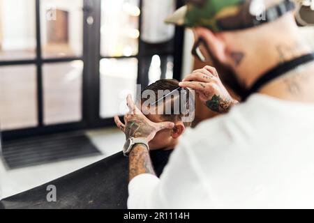 Die Jungs werden zuerst zu Männern im Friseursalon. Cropped hat einen süßen kleinen Jungen erschossen, der sich beim Friseur die Haare schneiden ließ. Stockfoto