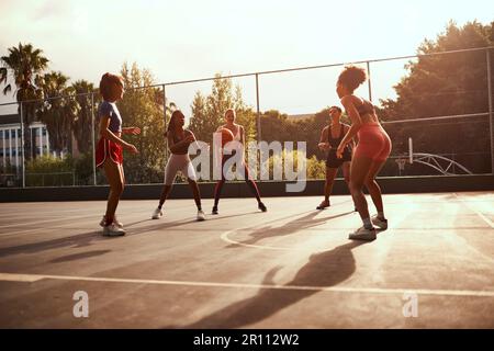 An wen kann ich mich wenden? Eine vielfältige Gruppe von Sportlerinnen, die tagsüber gemeinsam ein Wettkampfspiel mit Basketball spielen. Stockfoto