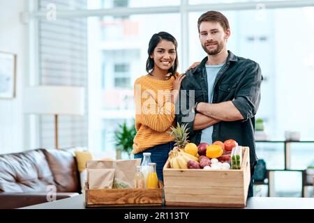 Gute Gesundheit ist die Grundlage eines guten Zuhauses. Ein glückliches junges Paar, das zu Hause seine gesunden Lebensmittel auspackt. Stockfoto