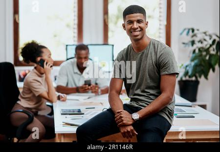 Unsere Meetings sorgen dafür, dass das Geschäft weitergeht. Porträt eines selbstbewussten jungen Geschäftsmanns mit seinem Team, der im Hintergrund ein Meeting abhält. Stockfoto