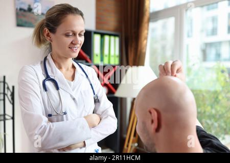 Weibliche Arztin für Trichologen, die männliche Patienten mit Haarausfall-Problem untersucht Stockfoto