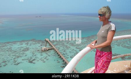 Eine Frau, die das Rote Meer mit Steg vom Leuchtturm Sanganeb im Sudan sieht Stockfoto