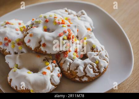 Ein Teller mit Süßigkeiten mit weißem Glasur, gelben roten Streuseln, hausgemachten Donuts, Rosquillas, traditionellen Anis-Donuts aus Spanien, die typischerweise zu Ostern gegessen werden Stockfoto