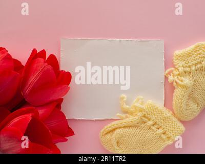 Tulpenblumen, Babyschühchen für ein Neugeborenes im Hintergrund mit Kopierraum Stockfoto