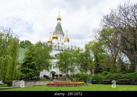 Sofia, Bulgarien. Mai 2023. Tulpen im russischen Kirchengarten mit den Kuppeln von St. Nicholas Kirche im Hintergrund Stockfoto