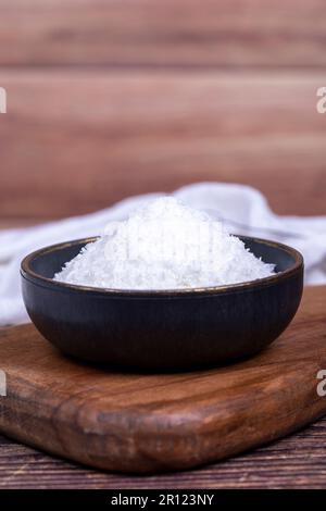 Kokosnusspulver. Gemahlene Kokosflocken auf Holzboden. Dunkle Schüssel mit getrockneter Kokosnuss. Schließen Stockfoto