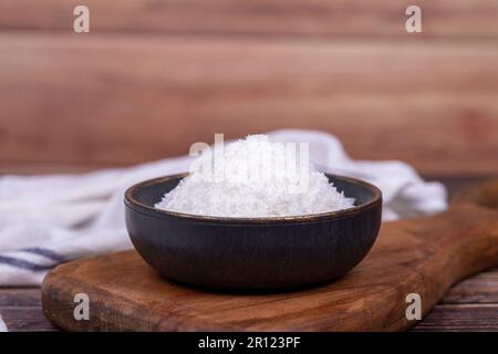 Kokosnusspulver. Gemahlene Kokosflocken auf Holzboden. Dunkle Schüssel mit getrockneter Kokosnuss Stockfoto