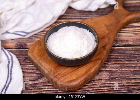 Kokosnusspulver. Gemahlene Kokosflocken auf Holzboden. Dunkle Schüssel mit getrockneter Kokosnuss Stockfoto