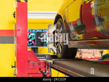 Automechaniker, der den Sensor während der Einstellung der Radausrichtung an der Reparaturwerkstatt installiert Stockfoto
