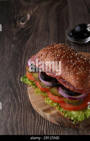 Foto-Sandwich mit Wurst- und Gemüseschichten auf dunklem Hintergrund Stockfoto