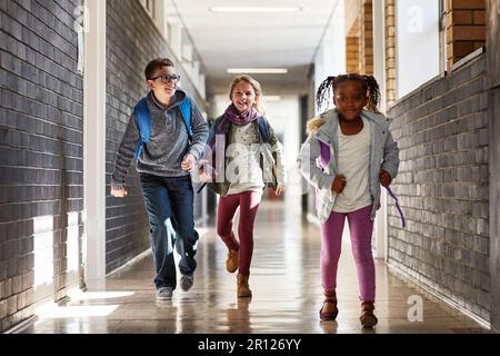 Wer zuerst in den Unterricht kommt. Grundschulkinder Rennen in den Korridoren der Schule. Stockfoto