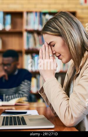 Bitte lassen Sie mich diesen Test nicht durchfallen... eine junge Frau, die gestresst aussieht, während sie hinter einem Laptop sitzt. Stockfoto