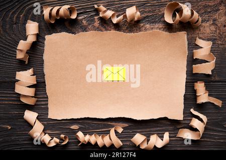 Zerrissenes Blatt Papier mit E-Mail-Symbol, Papierkunststil. Grußkarte, Brief, Einladungsmodell auf dunklem Holzhintergrund. Flach liegend, Draufsicht, kopieren Stockfoto