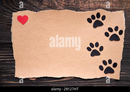 Postkarte mit Pfotenfußspur und rotem Herz, Papierkunststil. Tierliebeskonzept, Grußkarte, Einladungsmodell. Flach liegend, Draufsicht, Kopie Spac Stockfoto