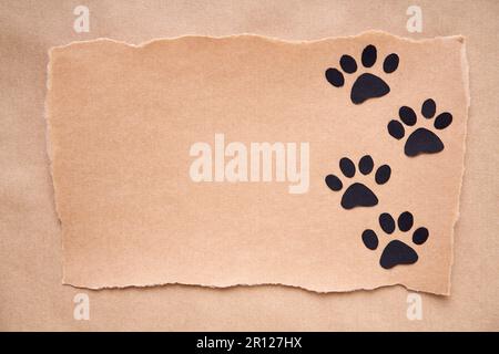 Postkarte mit Pfotenfußspur-Symbol, Papierkunststil. Tierliebeskonzept, Grußkarte, Einladungsmodell. Flach liegend, Draufsicht, Kopierbereich Stockfoto