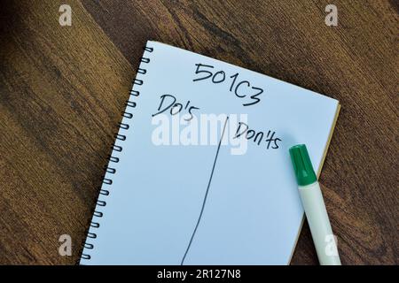 Das Konzept von 501C3 – Gebote und Verbote – Schreiben Sie auf ein Buch isoliert auf einem Holztisch. Stockfoto