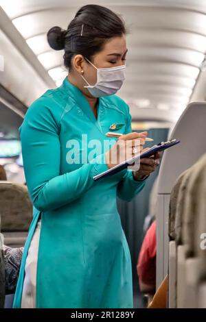 Vietnam Airlines Kabinenbesatzung trägt traditionelle AO dai Uniform auf dem Flug Stockfoto