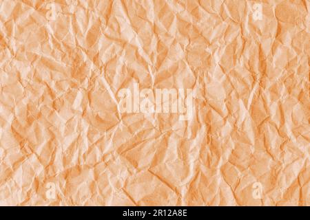 Zerknitterter orangefarbener Papierhintergrund aus recyceltem Papier. Abstrakter Hintergrund mit zerknittertem und faltenförmigem Hintergrund, Hintergrundbild mit Kopierbereich, Draufsicht. Stockfoto