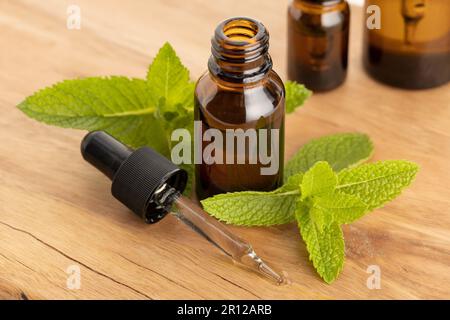 Bernsteinfarbene Pfefferminz-ätherische Ölflasche und Tropfer auf Holztisch. Pflanzliche Heilmittel Stockfoto