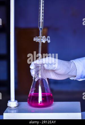 Der Student führt eine Säure-Basen-Titration durch, misst und fügt Lösungen mit Präzision bis zur Neutralisierung hinzu. Dieses Experiment hilft beim Erlernen von Chemis Stockfoto