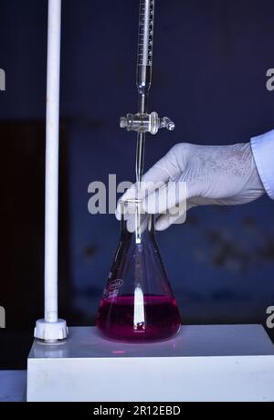 Der Student führt eine Säure-Basen-Titration durch, misst und fügt Lösungen mit Präzision bis zur Neutralisierung hinzu. Dieses Experiment hilft beim Erlernen von Chemis Stockfoto