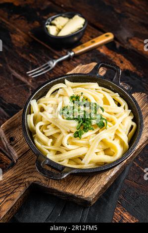 Deutsche Spaetzle-Eiernudeln mit Butter und Petersilie in einer Pfanne. Holzhintergrund. Draufsicht. Stockfoto