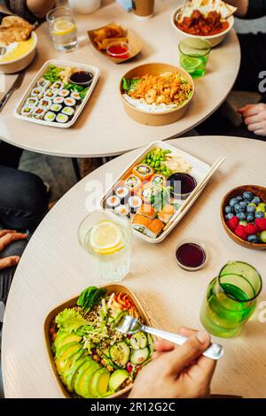 Eine Gruppe von Personen, die eine Mahlzeit zusammen an einem Tisch genießen, mit Tellern mit köstlichen Speisen vor jeder Person Stockfoto