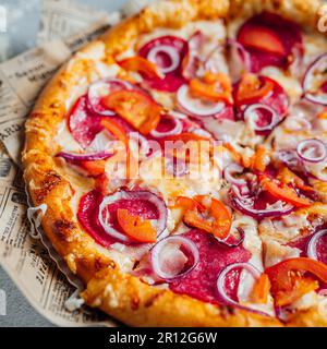 Eine frisch gebackene Pizza auf einem alten Papierkorb mit einer Zeitung Stockfoto