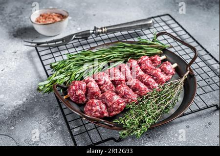 Roher türkischer Urfa-Kebab mit Kräutern, Gewürzen und Fleischgabel. Grauer Hintergrund. Draufsicht. Stockfoto