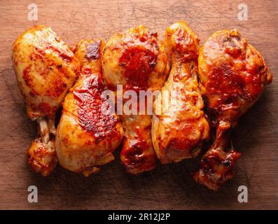 Gebratene Hähnchenschenkel auf einem Holzbrett, Draufsicht. Stockfoto