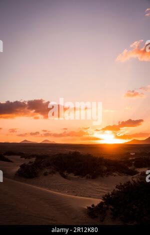Ein wunderschöner Sonnenaufgang, der von einer Sanddüne erfasst wird, mit einem sanften Hügel im Hintergrund Stockfoto