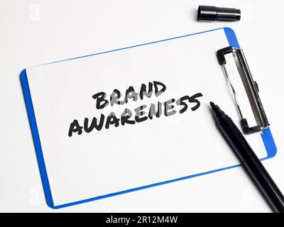 Ein Klemmbrett mit Stift, Tinte und Textmarkern vor einem festen Hintergrund mit den Worten „Markenbekanntheit“ in schwarzer Tinte Stockfoto