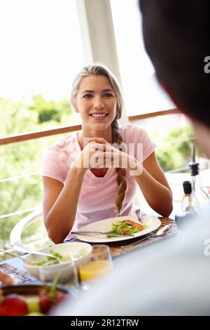 Eine Mahlzeit mit besonderen Menschen teilen. Eine attraktive Frau, die mit einer unbekannten Person zu Mittag isst. Stockfoto
