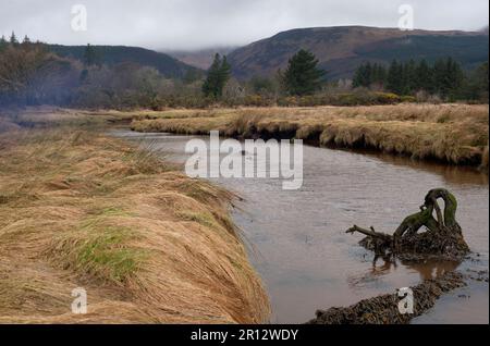 Ein Fluss in Brodick blickt auf die neblige Landschaft der Berge auf der Insel Arran in Schottland, neben dem Meer. Stockfoto