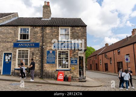 Menschen, die den steilen Hügel, Lincoln, Großbritannien, zu Fuß erkunden, eine beliebte Touristenattraktion in der Stadt, aufgrund ihrer unabhängigen Einzelhändler und des Charms der alten Welt. Stockfoto