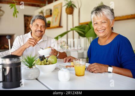 Essen Sie besser, fühlen Sie sich besser. Ein glückliches Seniorenpaar, das ein gemütliches Frühstück zusammen zu Hause genießt. Stockfoto