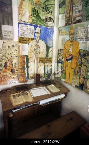 Sirnea, Brasov County, Rumänien, ca. 1999. Im Inneren des ethnografischen lokalen Museums mit einem alten Schulschreibtisch und Büchern und Poster, die Mitglieder der ersten Familie darstellen, die in der Gegend lebt, die Familie Bran, vermutlich Gründer mehrerer lokaler Dörfer. Stockfoto