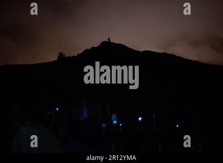 Die Silhouette einer Person steht auf dem Gipfel von Arthurs Seat während einer NVA Speed of Light Produktion auf dem Hügel in Edinburgh Stockfoto